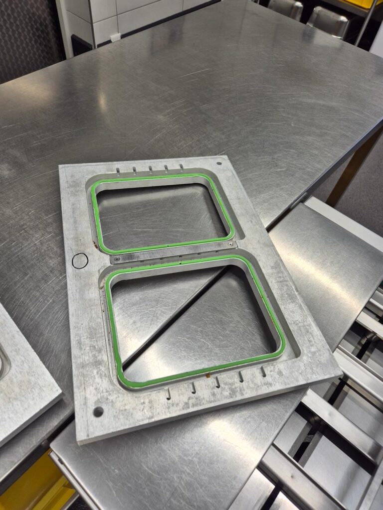 Sealgereedschap met twee vakken en groene afdichtingen op de werktafel